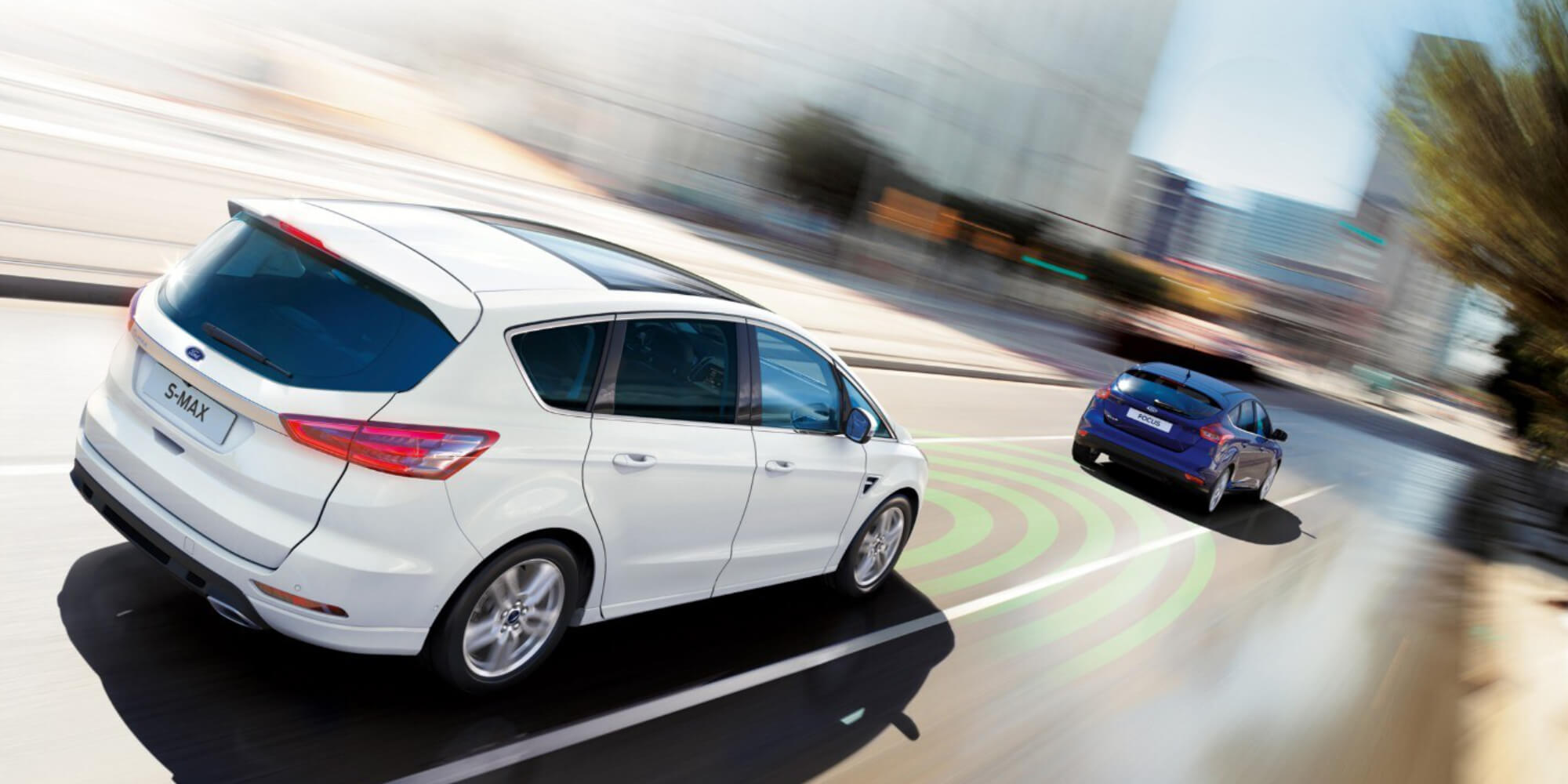 FORD S-MAX couleur blanc. Vue aux trois quarts, roulant derrière un véhicule bleu